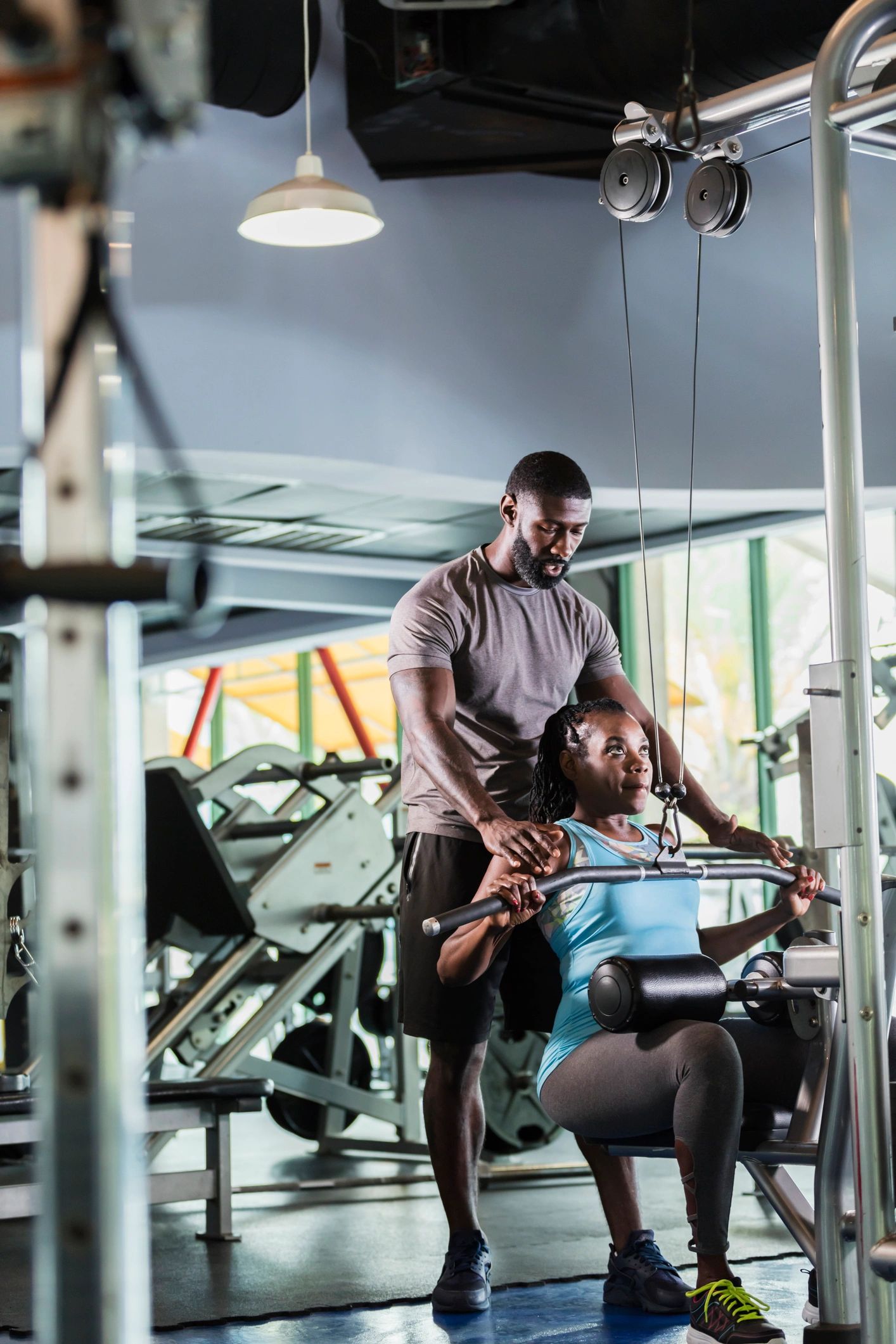 Trainer assisting a client with strength training in a gym