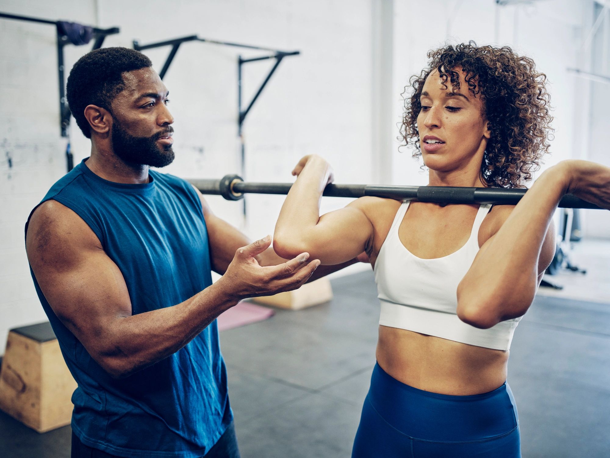Trainer coaching a woman during a strength exercise in a gym