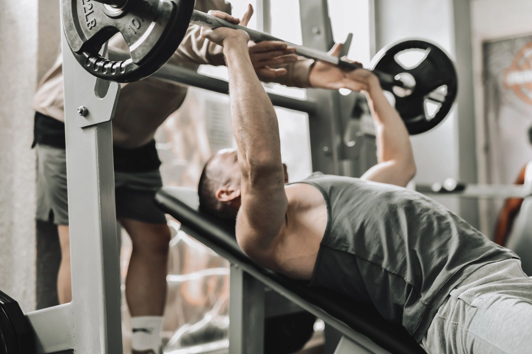 Trainer spotting a client during a bench press